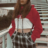 woman wearing a red cropped hoodie with chains over a white crop top and plaid pants