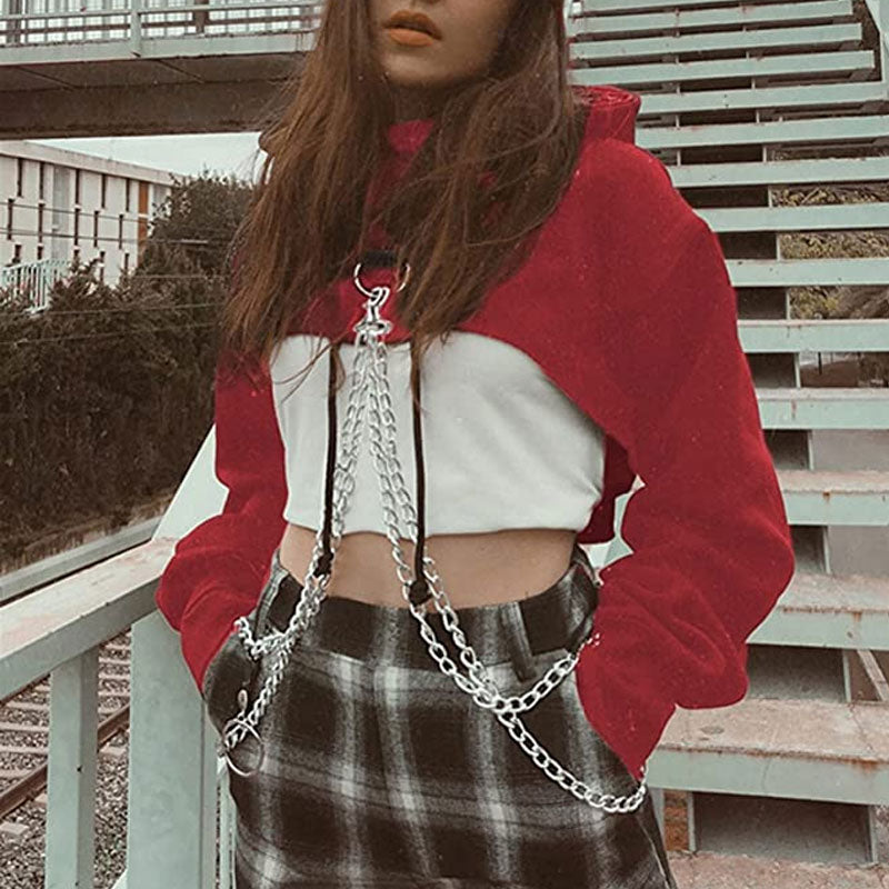 woman wearing a red cropped hoodie with chains over a white crop top and plaid pants