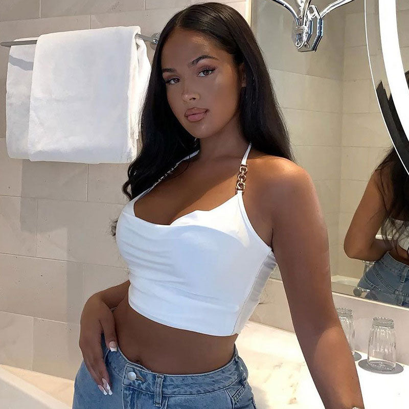 Woman in a white halter top and blue jeans posing in a bathroom