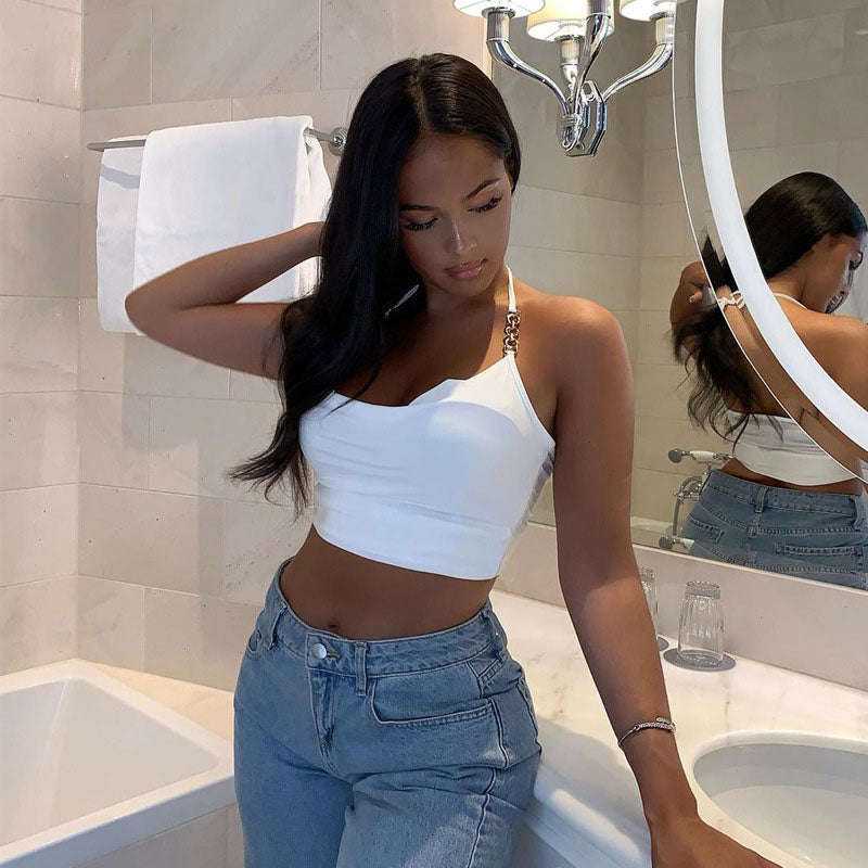 Woman in a white halter top and blue jeans looking down