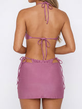 Back view of a woman wearing a rose bikini set with a matching ruched skirt.