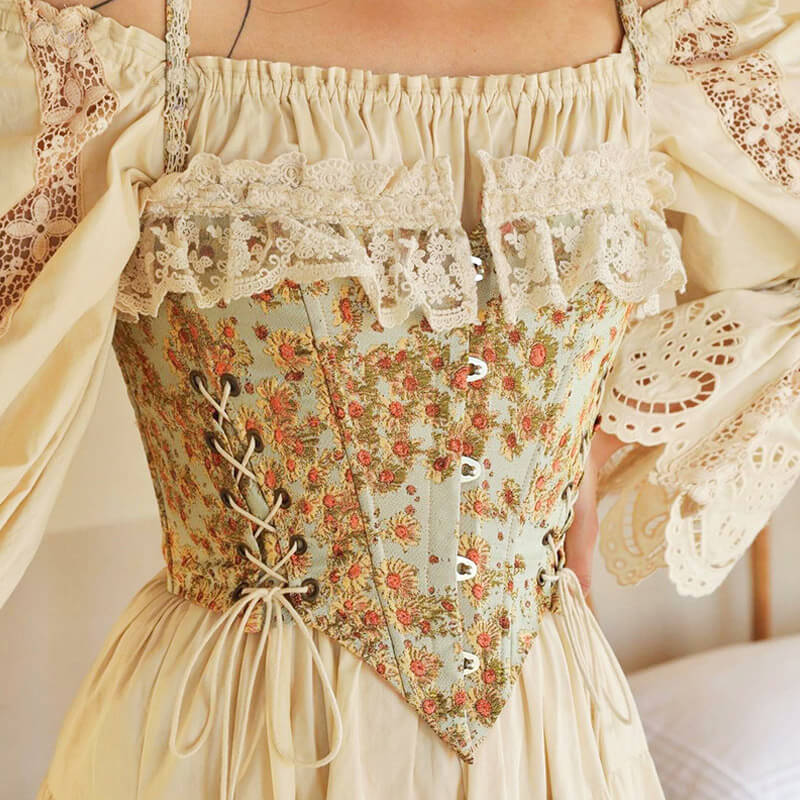 Close-up of a woman wearing a cream blouse with lace trim and a floral corset with ribbon lacing.