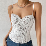 Woman wearing a white lace corset top with spaghetti straps and blue jeans.