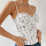 Woman posing with hands on hips, wearing a white lace corset top and blue jeans.