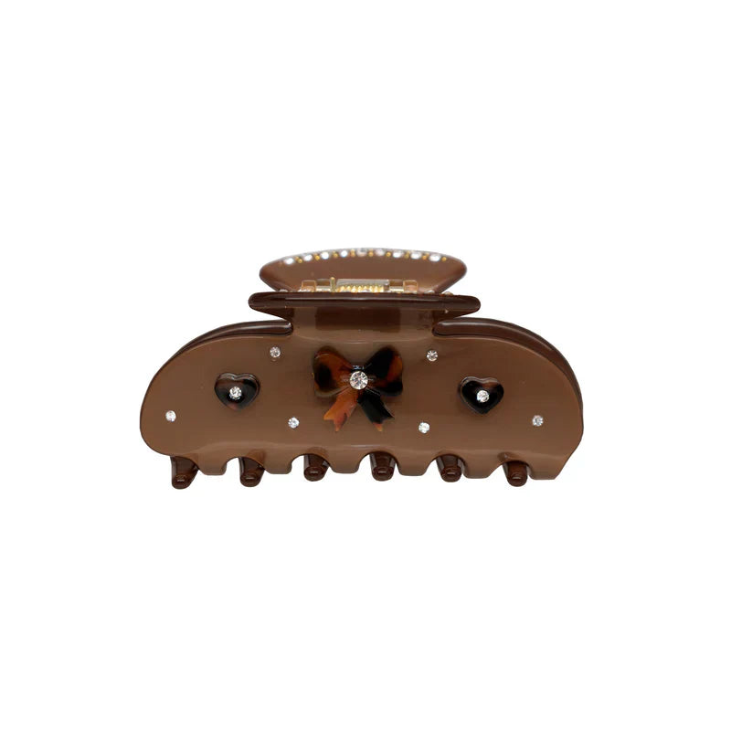 a close-up shot of a brown claw clip with a bow and heart accents