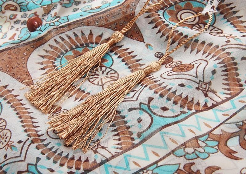 Close-up of a beige and teal paisley and floral print fabric with gold tassels.