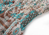 Close-up of the smocked waist of a beige and teal paisley and floral print dress.
