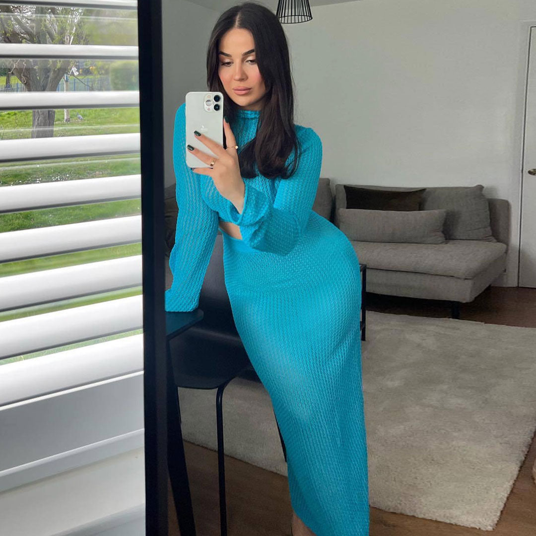 Woman taking a mirror selfie in a blue knit crop top and skirt in a living room.