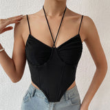 A woman wearing a black halter neck ruched corset top with denim jeans.