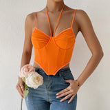 Model wearing an orange ruched mesh corset top with a plunging halter neckline and spaghetti straps, paired with ripped blue jeans. She is holding light pink and white roses in her left hand and wearing gold rings.