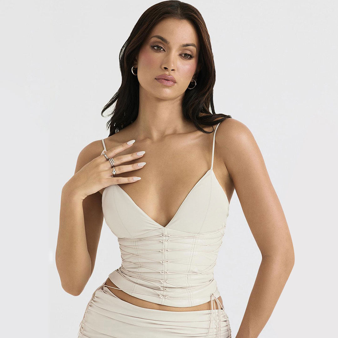 Close-up of a woman in a cream V-neck top, highlighting the ruched texture and delicate lace-up front.