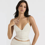 Close-up of a woman in a cream V-neck top, highlighting the ruched texture and delicate lace-up front.
