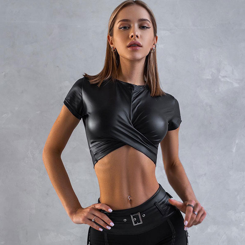 Woman wearing a black faux leather cropped top with a twist front and short sleeves.
