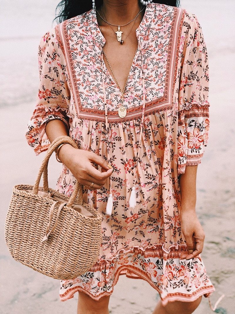 Close-up of a woman in a floral peach dress with a straw bag