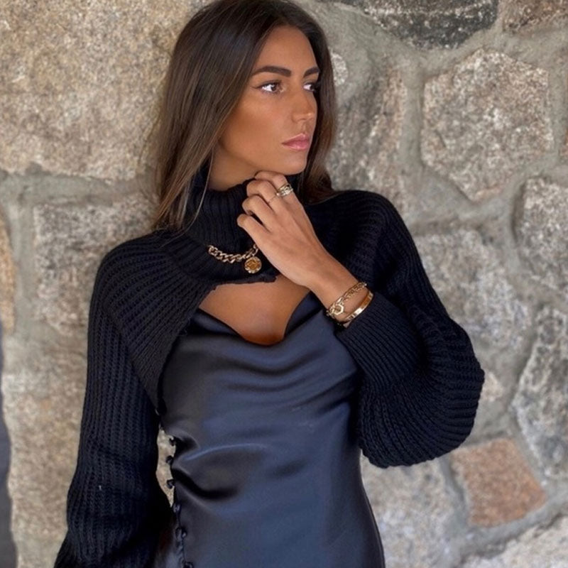 woman wearing a black cropped sweater with a turtleneck and cut-out detail over a black slip dress