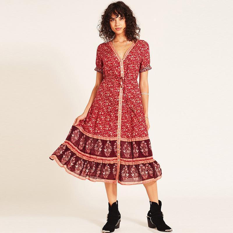 Woman wearing a red floral midi dress with a burgundy hem panel, posing against a white background.