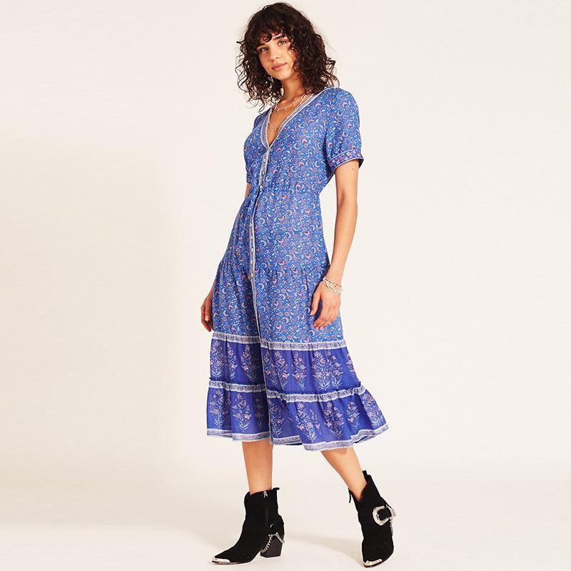 Woman wearing a blue floral midi dress with a purple hem panel, posing against a white background.