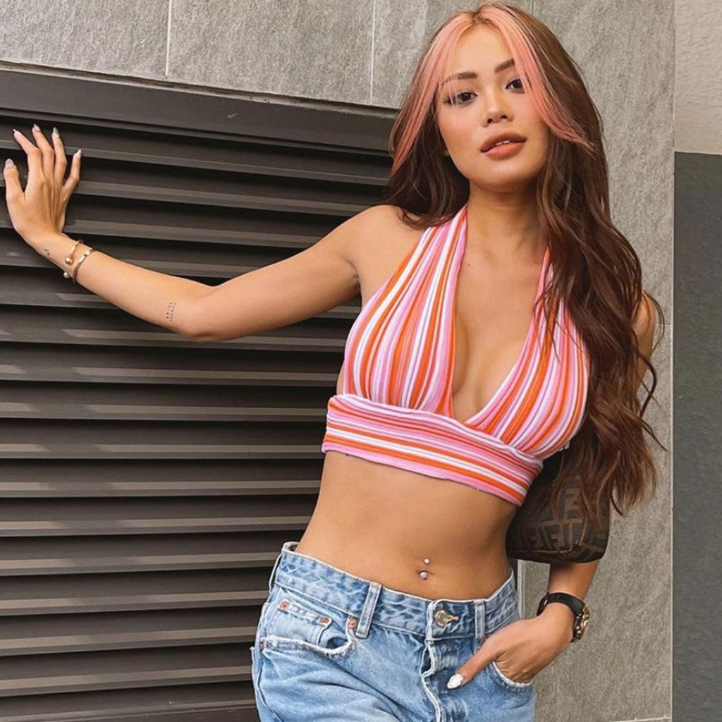 woman in pink and orange striped halter top and distressed blue jeans