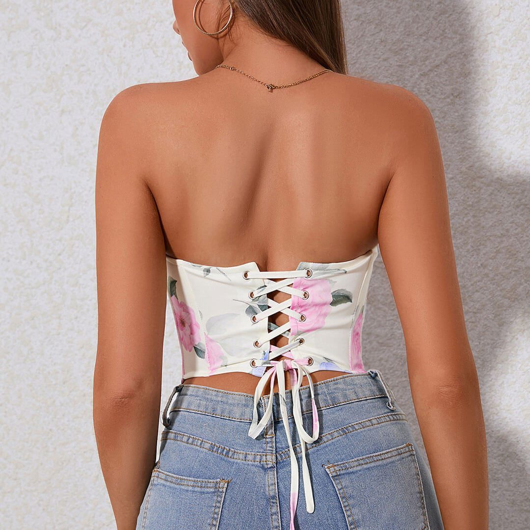 Back view of a woman wearing a white floral corset top with a lace-up closure.