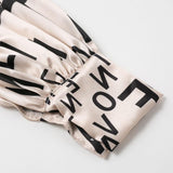 close-up of the cuff of a beige dress with a black letter print