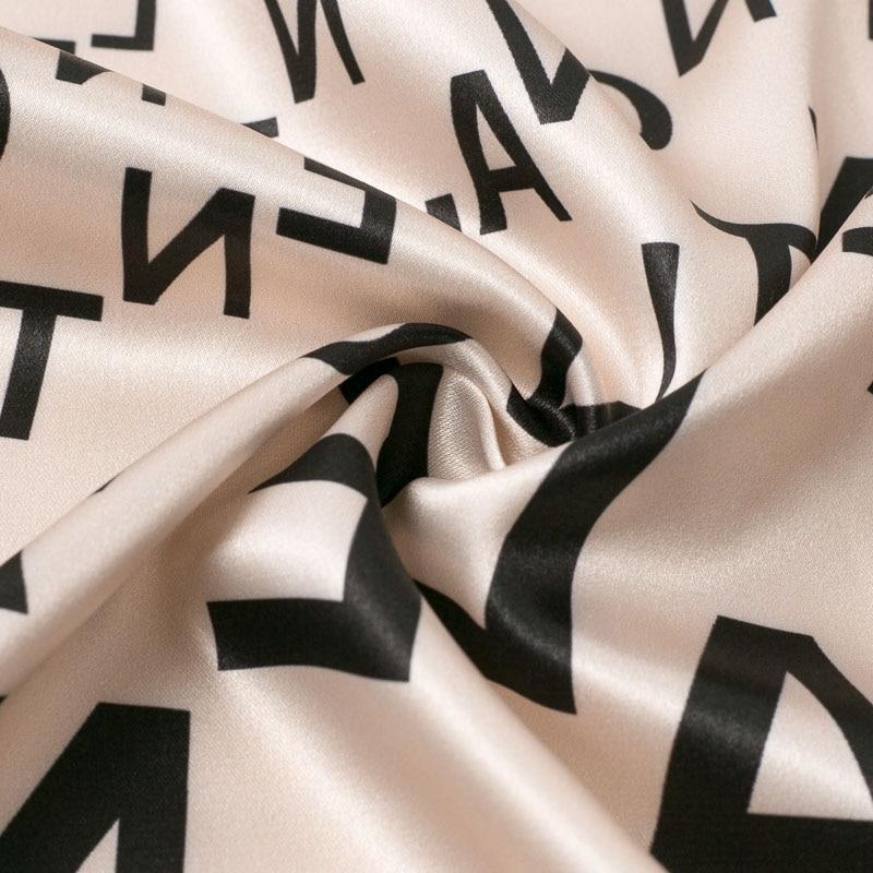 close-up of the fabric of a beige dress with a black letter print