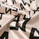 close-up of the fabric of a beige dress with a black letter print