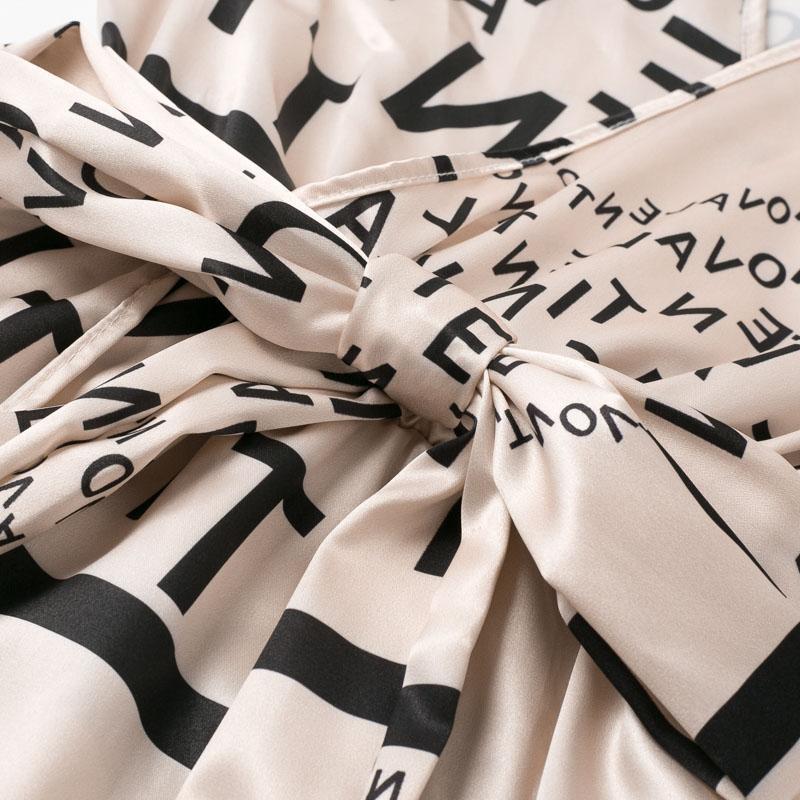close-up of the tie waist of a beige dress with a black letter print