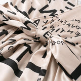 close-up of the tie waist of a beige dress with a black letter print
