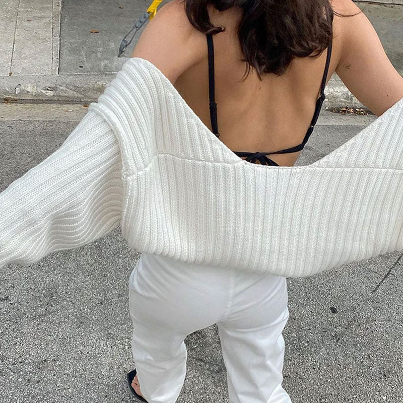 Woman wearing a white ribbed knit shrug over a black bra