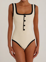 woman wearing a cream and black ribbed one-piece swimsuit with a square neckline and button detailing