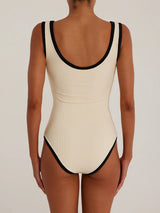 back view of a woman wearing a cream and black ribbed one-piece swimsuit