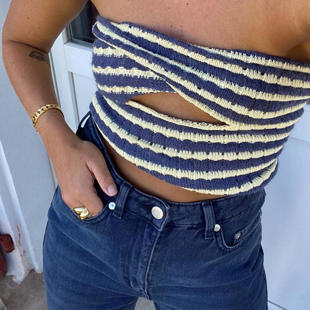 Close-up of a woman wearing a blue and white striped strapless top with a cut-out detail and dark wash jeans.