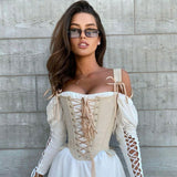 Woman wearing a white off-the-shoulder dress with a beige corset and long lace-up sleeves