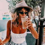 woman wearing a white ruched tank top and denim shorts